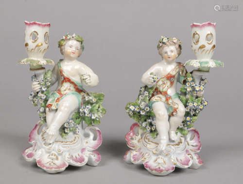 A pair of Chelsea Derby figural chamber sticks painted in coloured enamels. Each surmounted with a