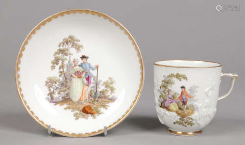 A Meissen cup and saucer moulded with prunus blossom and having scrolling handle. Painted with six