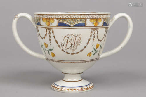 A Swinton pottery twin handled loving cup. Painted in coloured enamels with a flower and gadrooned