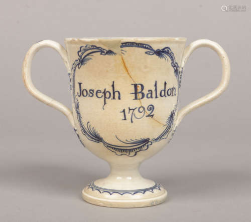 An inscribed and dated pearlware pedestal loving cup with loop handles having feathered terminals.