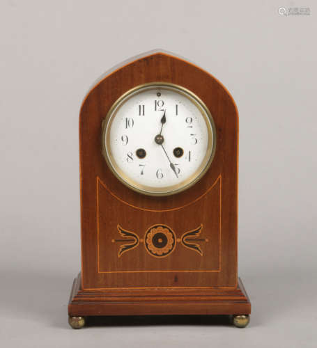 An Edwardian inlaid mahogany cased mantel clock of lancet form. With enamel dial and raised on brass
