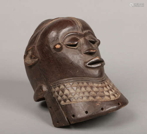 A West African carved hardwood tribal helmet mask. With domed coiffure and wide geometric banded