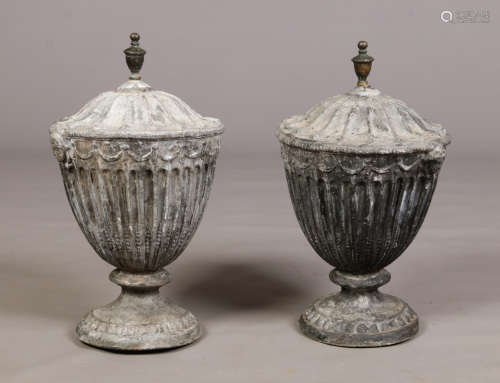 A pair of Georgian lead garden urns in the manner of Robert Adam. With twin mask handles, of