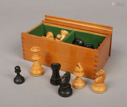 A carved and ebonized wooden chess set of Staunton type with weighted pieces and in pine box with