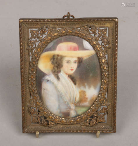 An early 20th century ivory portrait miniature in pierced brass frame depicting a seated lady.