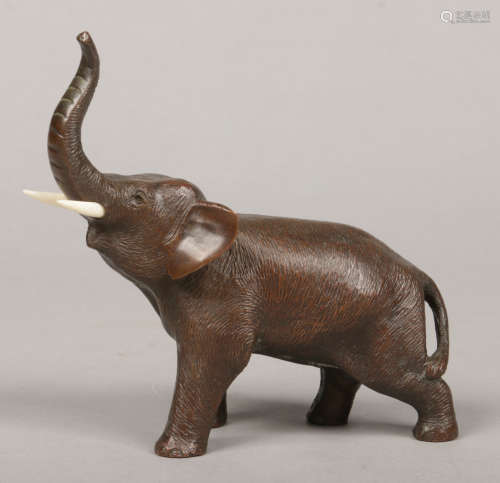 A Japanese Meiji period small bronze sculpture of an elephant with bone tusks. Signed to the