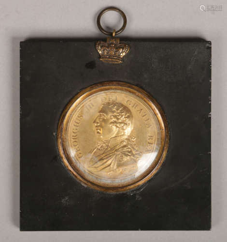 A gilt metal commemorative medal for King George III in ebonized frame, 5.5cm diameter.