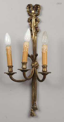 A set of four cast and gilt bronze three branch wall lights each modelled with ribbon supports and