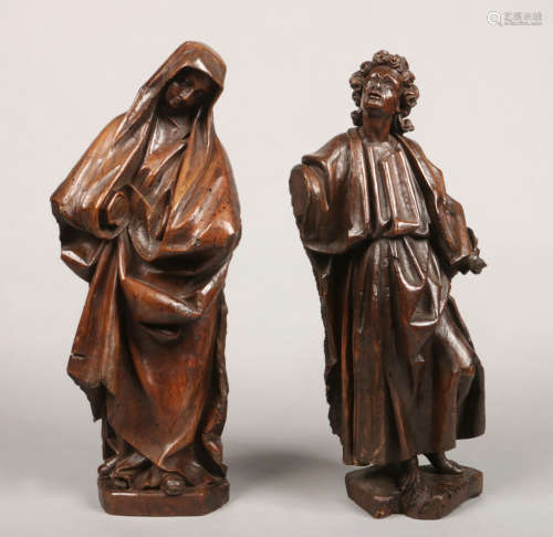 A pair of early 19th century Continental carved wooden statues formed as Saints dressed in flowing