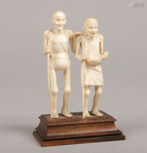 A 19th century Indian carved ivory figure group on hardwood plinth. Formed as an emaciated old man