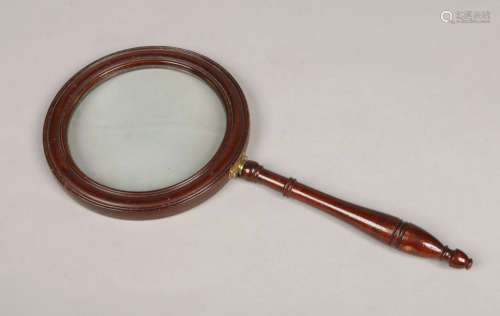 An early 20th century oversized hand held magnifying glass. In reeded carved mahogany frame with