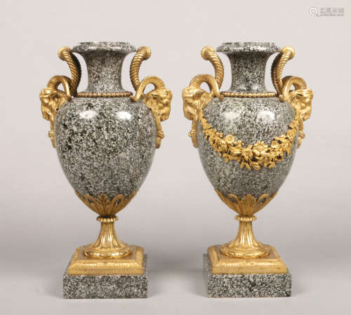 A pair of Neo-Classical style porphyry marble urns with bronze mounts. Having ram mask handles and