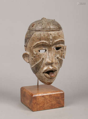 A West African ceremonial tribal mask decorated with kaolin pigment and raised on an associated
