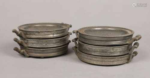 A set of six Victorian pewter warming plates. With twin scrolling handles and gadrooned borders,