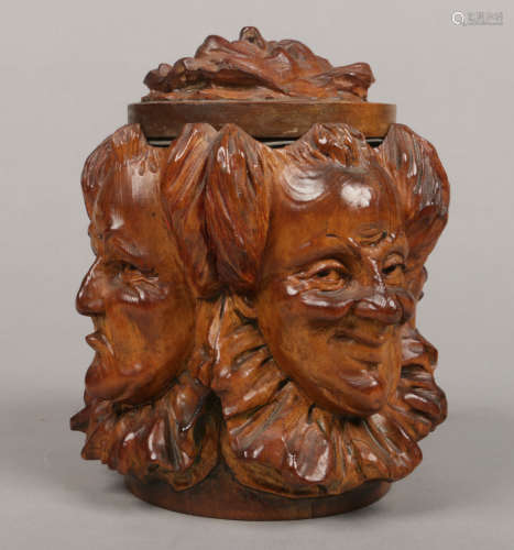 A mid 20th century novelty carved treen tobacco jar decorated with five clown masks and having