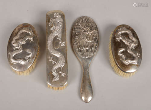 Three Chinese silver backed clothes brushes and a back from a hand mirror. The brushes embossed with