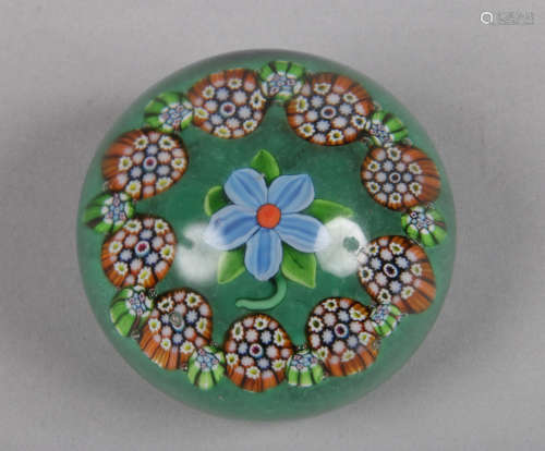 A Paul Ysart glass paperweight decorated with a flower under a cane garland over a green ground c.