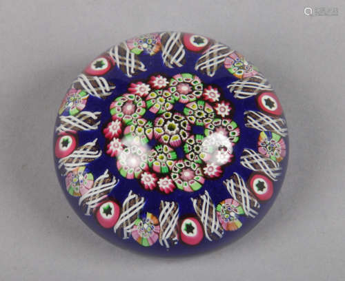 A Paul Ysart glass paperweight decorated with multi coloured canes on a dark blue ground. Pontil