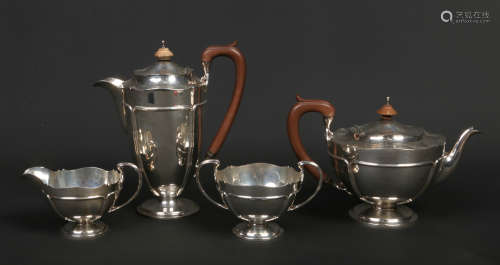 A George V silver four part tea service by Adie Bros. Ltd. With scalloped tops, piped cartouches and