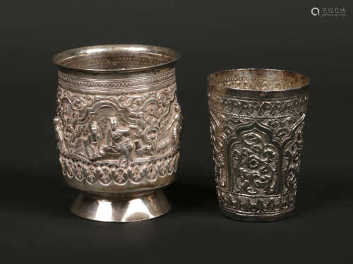 Two Indian silver beakers, one raised on a spreading foot. Both with repousse decoration, the footed