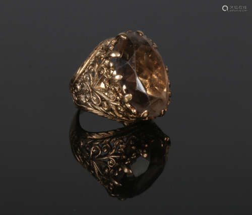 A 9 carat gold smokey quartz cocktail ring with scrolling openwork shoulders. Size F.
