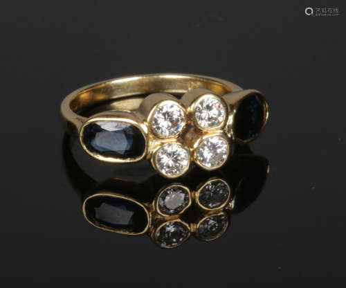 An 18 carat gold ring set with a cluster of four brilliant cut diamonds flanked by a pair of ovoid