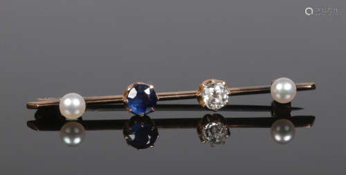 A yellow metal bar brooch set with a diamond and sapphire flanked by two pearls. Diamond