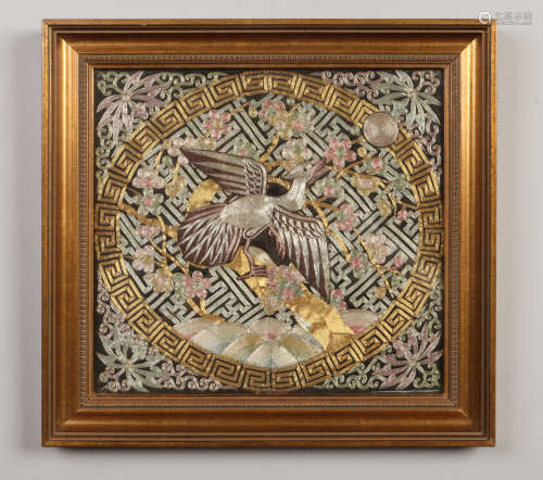 A gilt framed Chinese silk rank badge with gold and silver thread and depicting a crane under a
