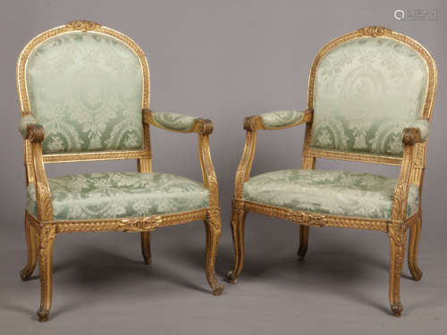 A pair of mid 19th century English giltwood open armchairs. With green silk upholstery and raised on
