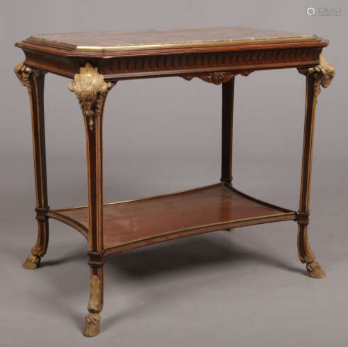 A Continental marble top walnut two tier centre table. With canted corners having carved ram masks