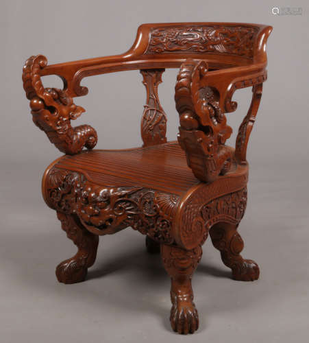 A 20th century Chinese hardwood armchair. Profusely carved with turtles, cloud scrolls, dogs of fo