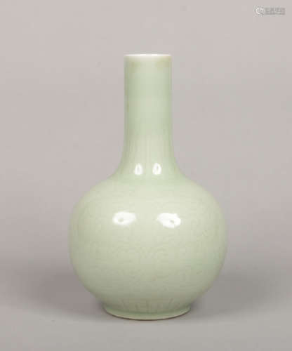 A Chinese celadon bottle vase. Carved in relief with stiff leaves to the collar and lotus scrolls to