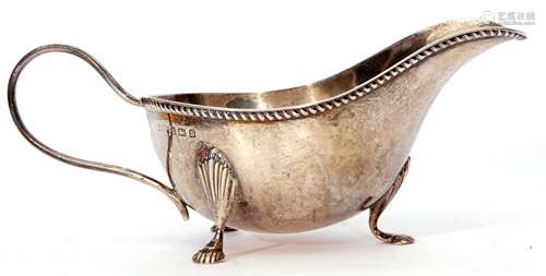 George VI gravy boat of typical form with cast and applied rim, strapwork handle and raised on three