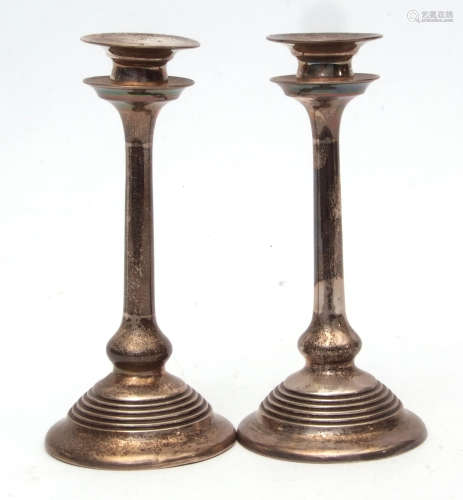 Two early 20th century single candlesticks, each with detachable sconces over flared drip pans and