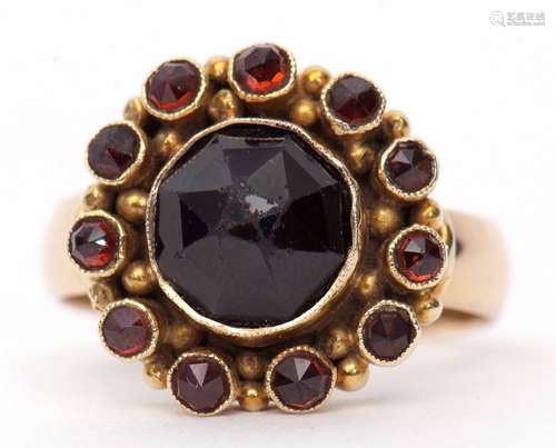 Garnet cluster ring featuring a large central garnet of rose cut, 8.7mm diam, within a surround of