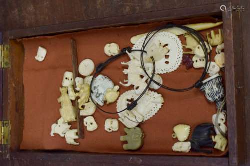 Small wooden display case containing various small ivory carved items, all early 20th century, the