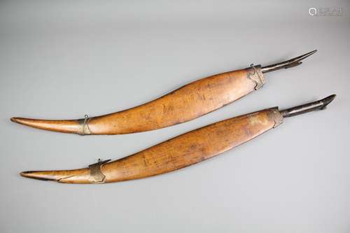 Two South Asian Swords, with water-buffalo handles, the single-edged blades both have decorative etching and swept to the right, complete with flat wooden scabbards