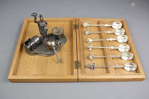 A Silver Plate Military Cruet Set; the set comprising a pepper in the form of a cannon, salt in the form of a cannon ball and a mustard in the form of a drum with a military figure holding a torch flame, together with a box of silver plate teaspoons