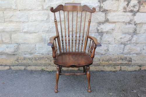 An Oak Fireside Chair, turned spindle back supports, swept arms with decorative carving, turned legs and stretchers