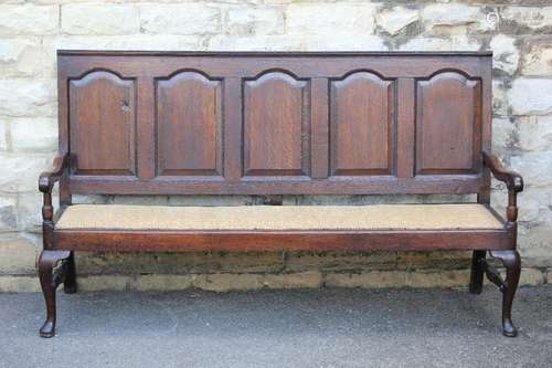 An Antique Oak Settle, panel back with swept arms, supported on turned stretchers and pad foot, approx 183 l x 81 w x 107 cms h, with cream upholstered seat