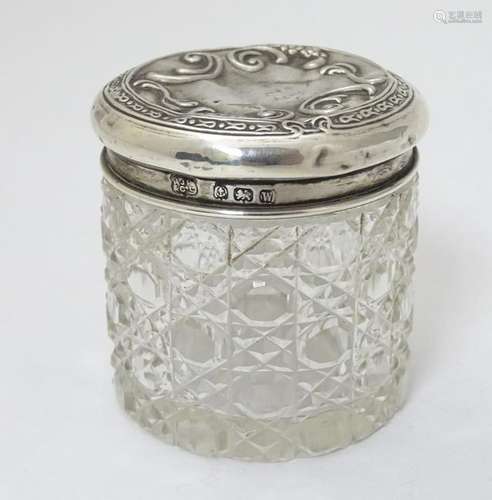 A cut glass dressing table pot with silver top