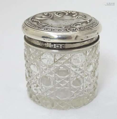 A cut glass dressing table pot with silver top