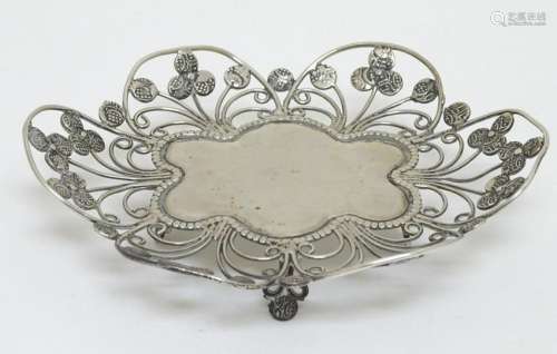 A white metal dish of floral form with open work