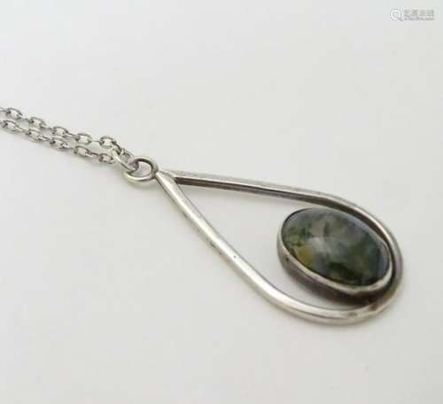 A silver pendant and chain, the pendant set with moss