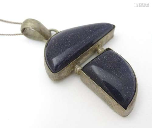 A modernist pendant set with polished hardstone detail