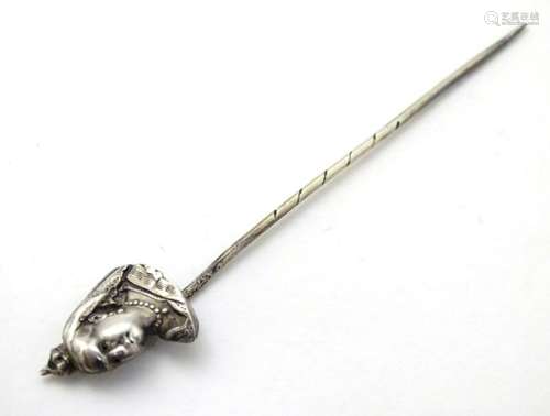 A white metal stick pin surmounted by image of Queen