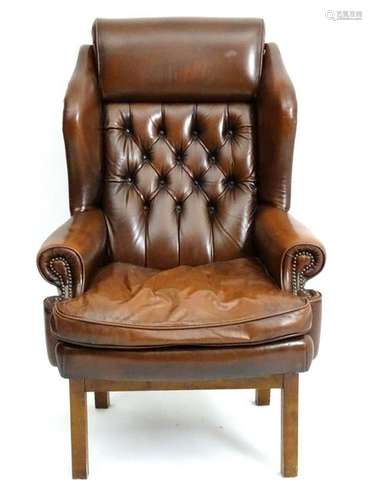 A 21stC leather wingback armchair with a deep buttoned