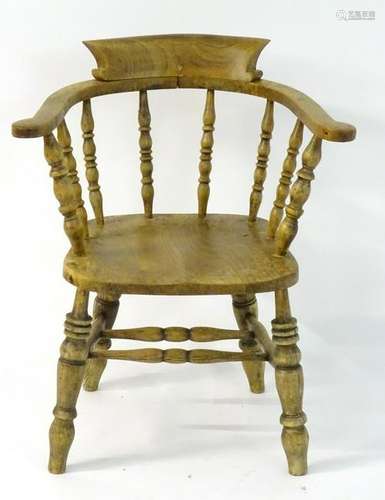 An early 20thC elm smokers bow chair, standing on