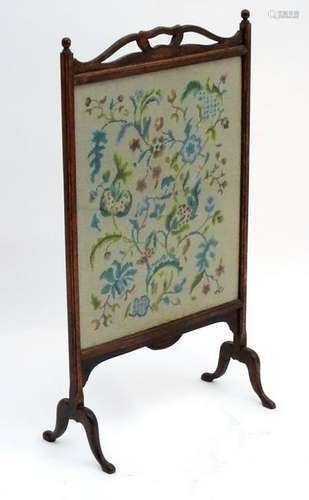 An early 20thC oak fire screen with a shaped handle and