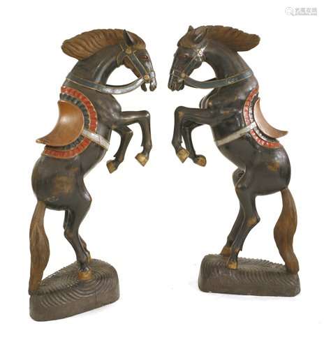 A pair of large carved wooden and polychrome decorated prancing horses,